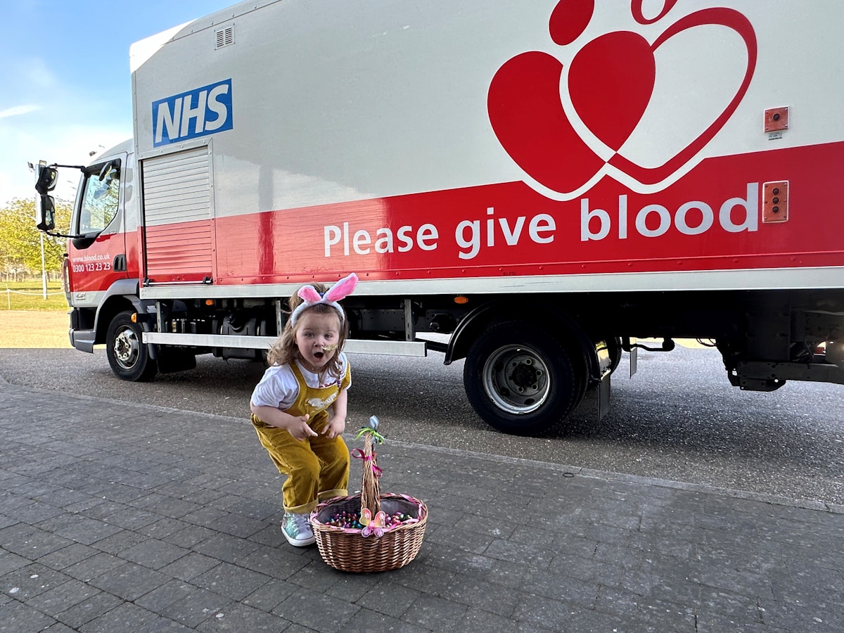 Etta giving out Easter eggs at the hospital in front of a Please Give Blood truck
